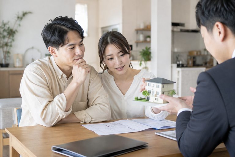 住宅の模型を前に、男女が家探しについて相談している様子